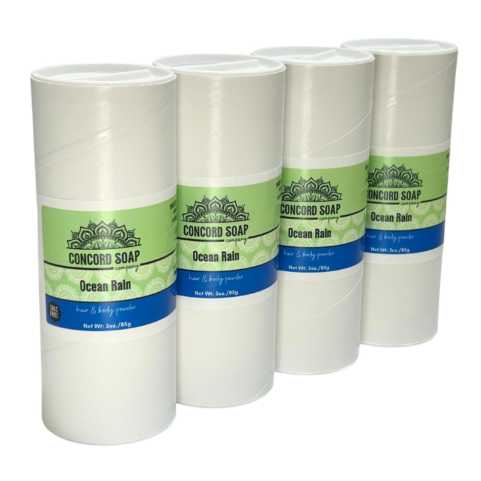 Four eco-friendly white cardboard shakers of handmade Ocean Rain hair and body powder by Concord Soap Company, displayed on a solid white background. Each container has a green and white label featuring the company logo and product name. The tubes are arranged side by side in a row, showcasing the product packaging and branding. Natural talc-free powder in the ocean rain fragrance for a fresh, breezy scented skincare and personal hygiene product.