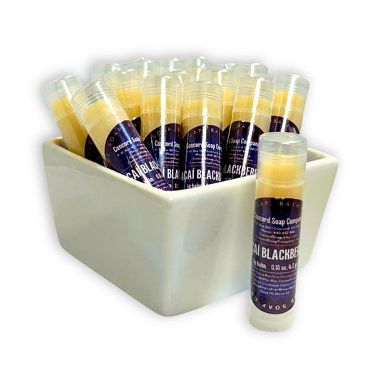 Handmade Açaí Blackberry lip balm tubes in bowl with one tube in front. This flavor of natural lip balms by Concord Soap Company is labeled with a deep purple circular label, with product and company details, and is shrink wrapped for safety. Listing is for ONE lip balm.
