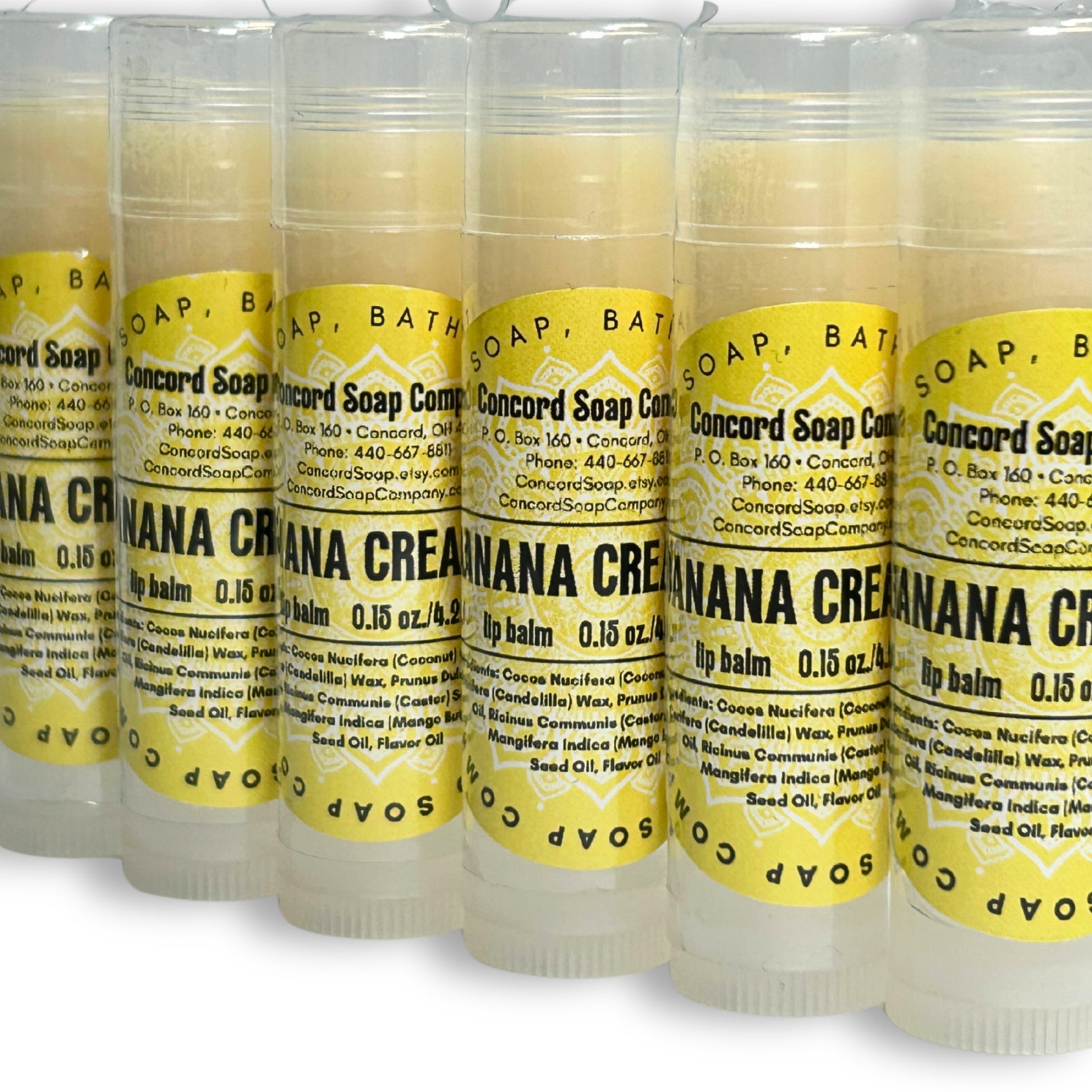 View of Handmade Banana Cream Pie lip balm tubes arranged in a diagonal line. These natural lip balms by Concord Soap Company have a bright yellow circle label with product and company details and is also shrink wrapped for safety.