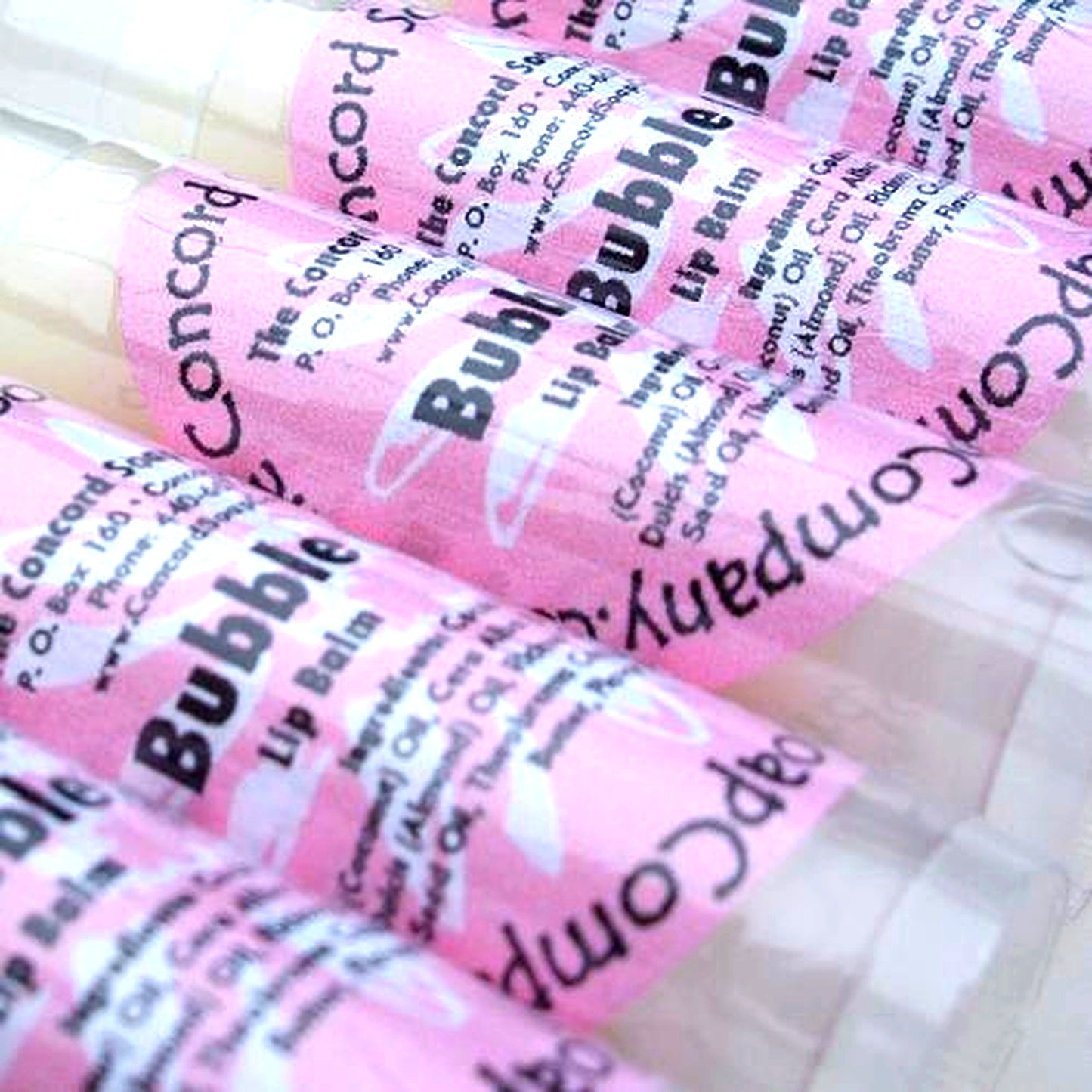 Close-up of Bubble Gum scented lip balm tubes with pink labels, arranged together on a clean white backdrop.