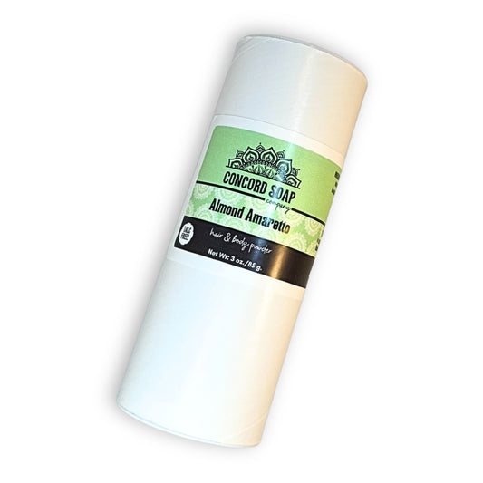 One eco-friendly white cardboard shaker of handmade Almond Amaretto hair & body powder by Concord Soap Company, displayed on a solid white background. The container has a green & white label featuring the company logo and product name. The tube is arranged askew, at a slight angle, showcasing the product packaging and branding. Natural talc-free powder in the intoxicating almond amaretto fragrance for a sweet, cherry almond scented skincare and personal hygiene product.