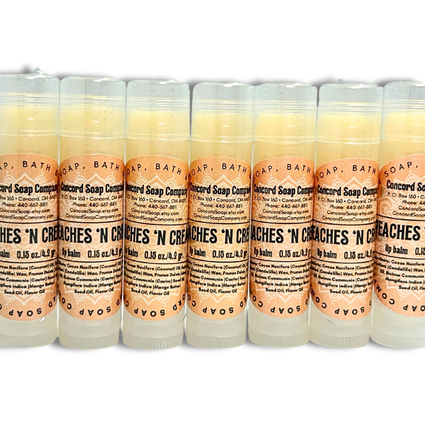 A line of Handmade Peaches & Cream lip balm tubes. Each of these natural lip balms by Concord Soap Company has a peach-colored circle label with product and company details and is shrink wrapped for safety.