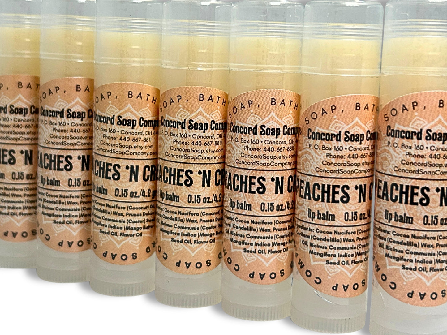 Handmade Peaches & Cream lip balm tubes angled in a slight diagonal line. Each of these natural lip balms by Concord Soap Company has a peach-colored circle label with product and company details and is shrink wrapped for safety.