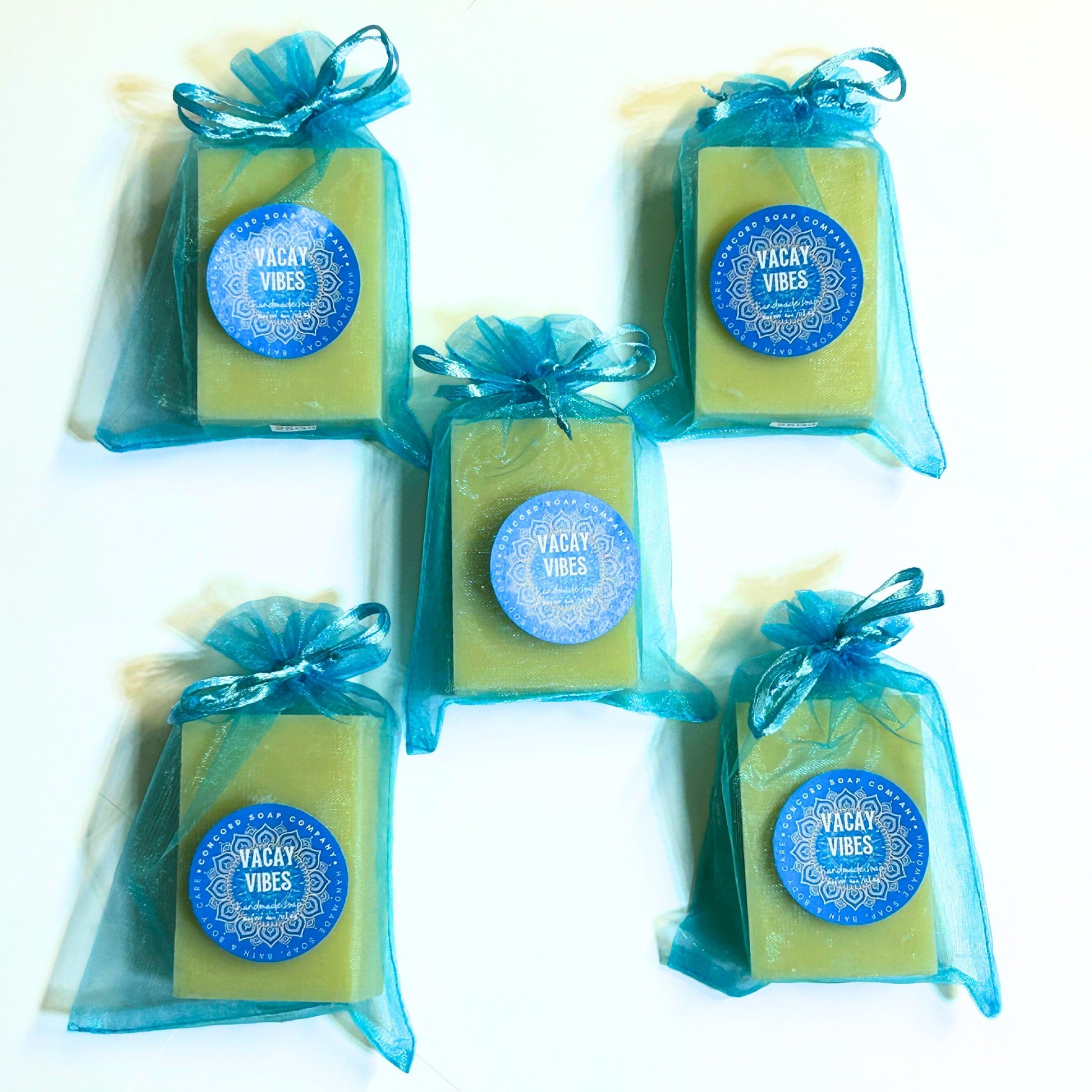 Five Vacay Vibes handmade soap bars in aqua blue organza bags arranged flat on white background, vegan cold process beach-scented soaps