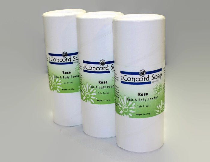 Three eco-friendly white cardboard shakers of handmade Rose hair and body powder by Concord Soap Company, displayed on a solid white background. Each container has a green and white label. Natural talc-free powder in a true rose petal fragrance for fresh, floral scent skincare and personal hygiene.
