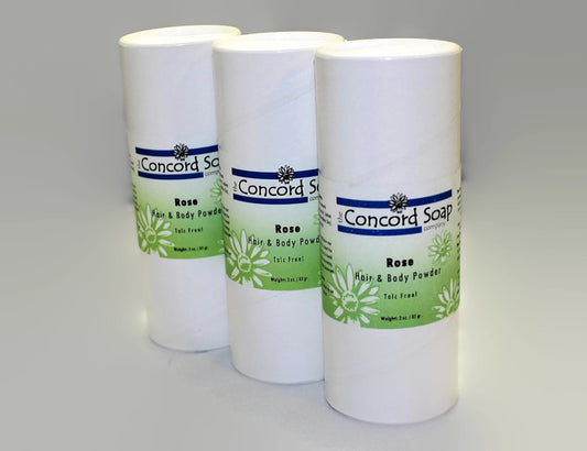 Three eco-friendly white cardboard shakers of handmade Rose hair and body powder by Concord Soap Company, displayed on a solid white background. Each container has a green and white label. Natural talc-free powder in a true rose petal fragrance for fresh, floral scent skincare and personal hygiene.