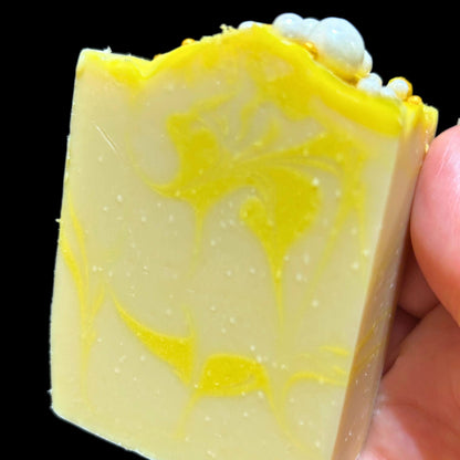 Side view of Apple Honey Champagne soap bar held in hand showing yellow swirl pattern.