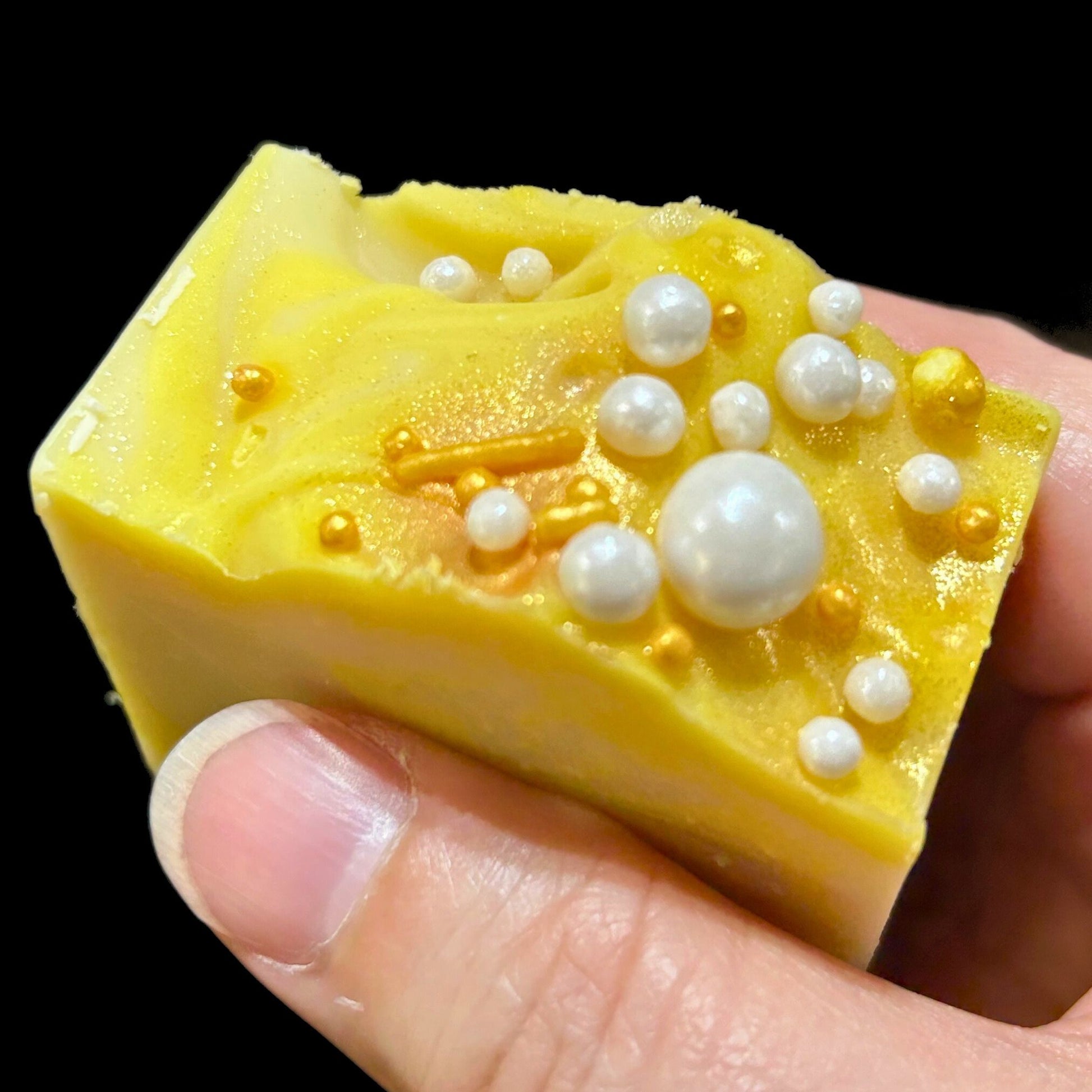 Close-up of Apple Honey Champagne soap bar held in hand showing gold mica and pearl decorations.