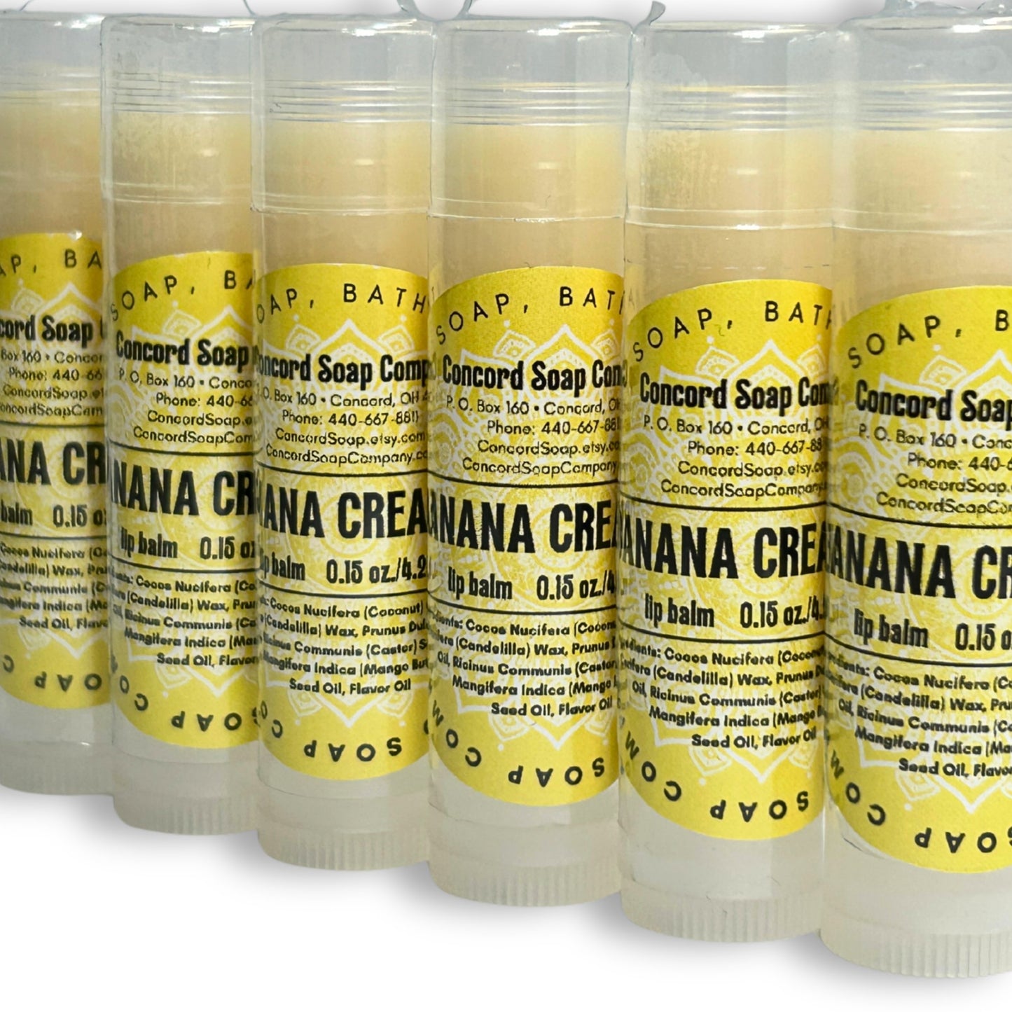 View of Handmade Banana Cream Pie lip balm tubes arranged in a diagonal line. These natural lip balms by Concord Soap Company have a bright yellow circle label with product and company details and is also shrink wrapped for safety.