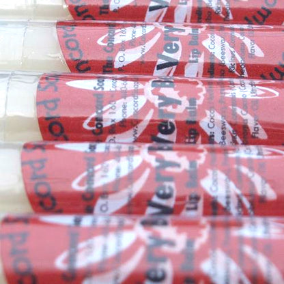 Close-up of Very Berry Sparkle lip balm tubes with red labels organized in a neat row.