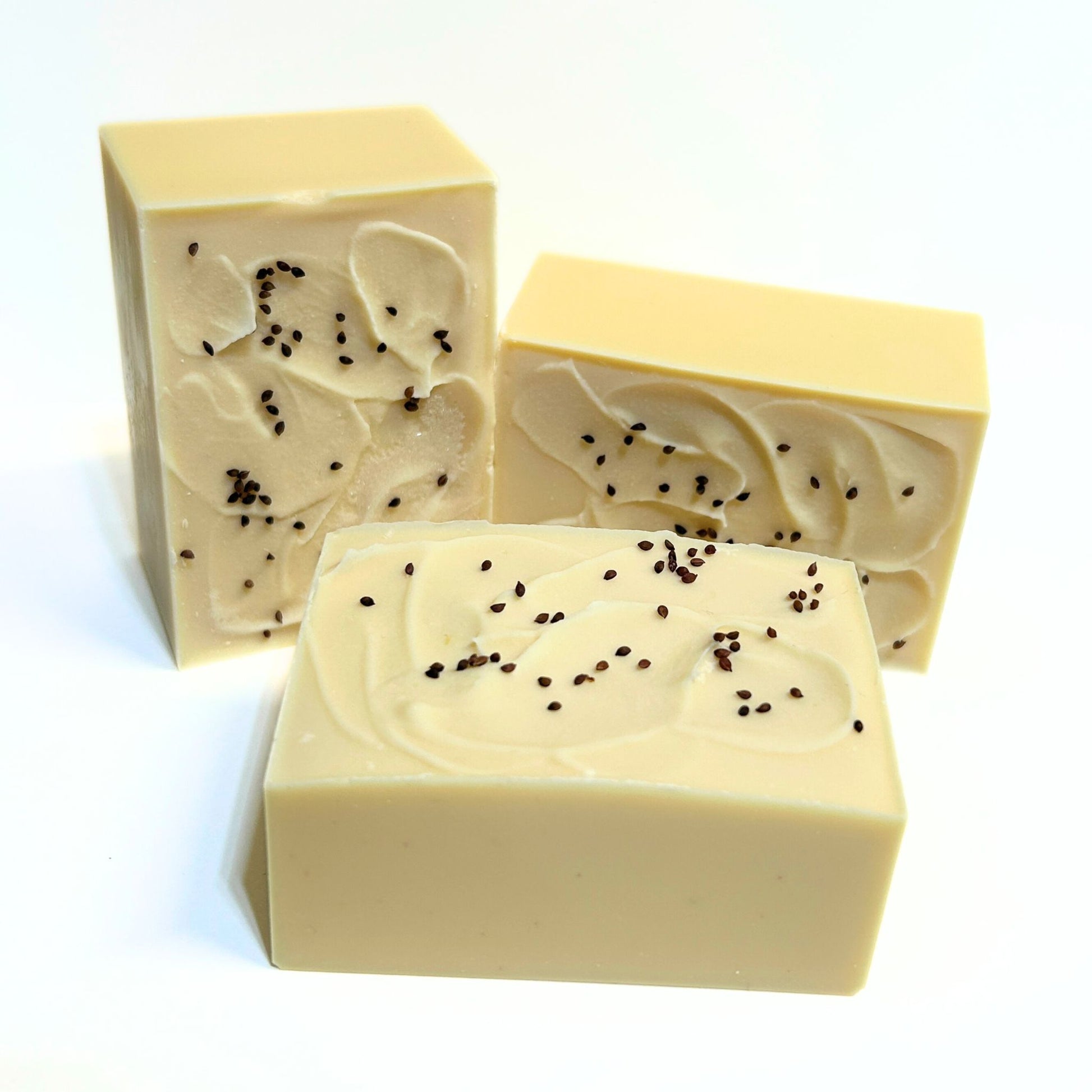 Three unwrapped Cranberry soap bars with cranberry seeds sprinkled on top.