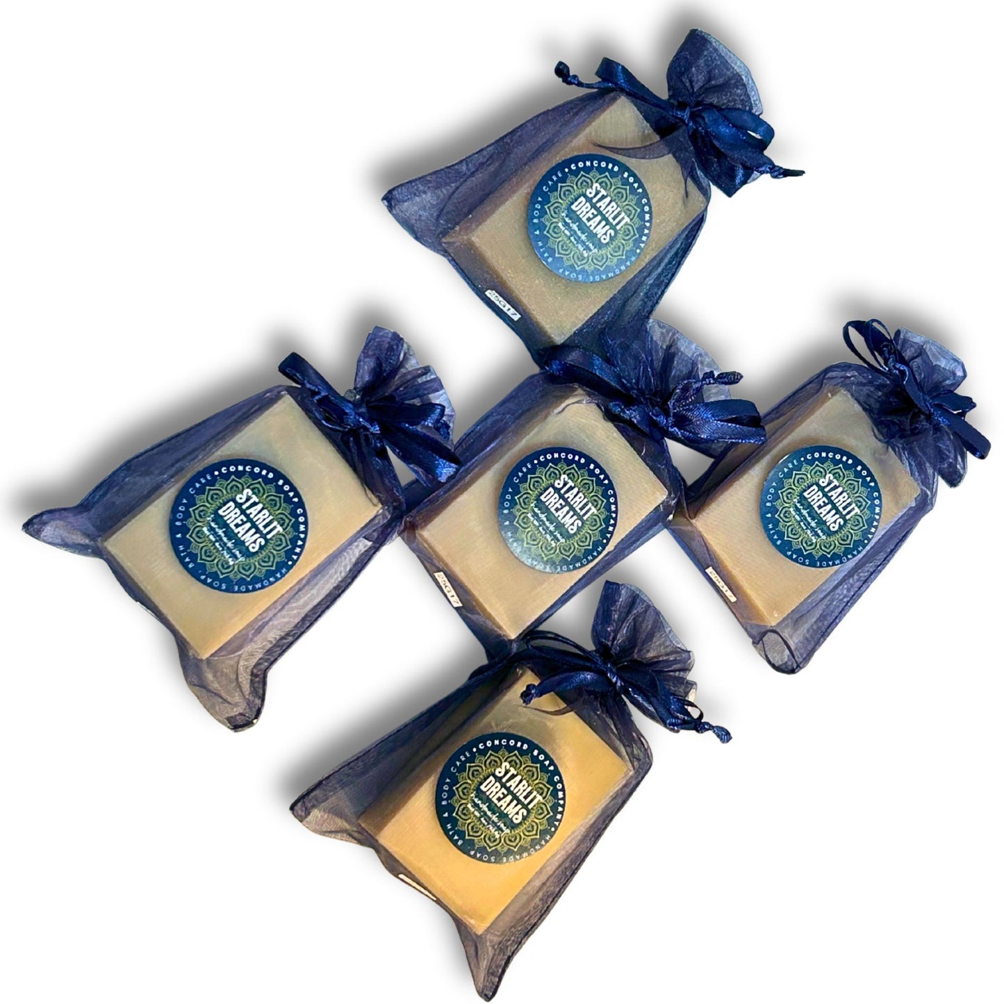 Flat-lay, top-down view of five Starlit Dreams vegan cold process soap bars in navy organza bags.