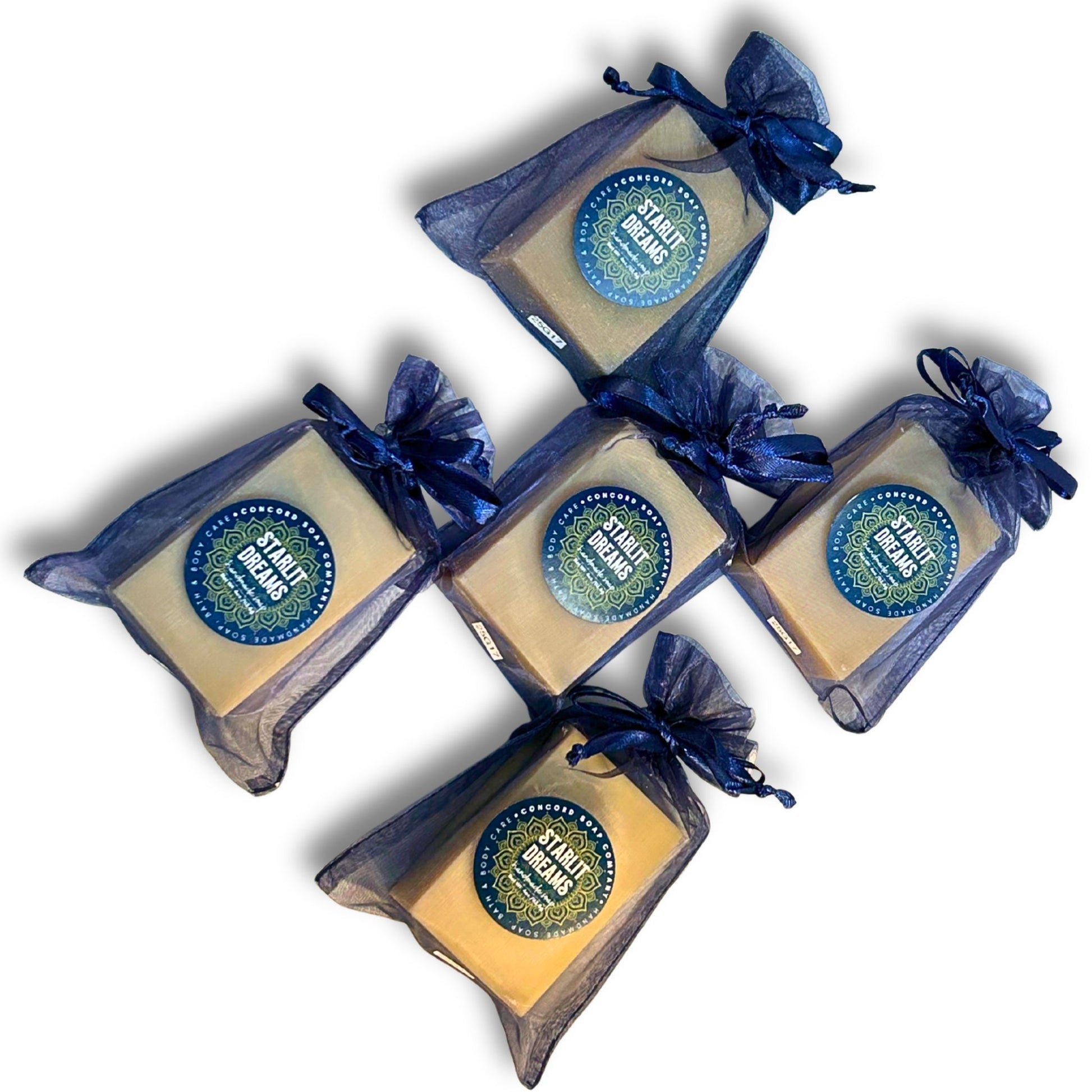 Flat-lay, top-down view of five Starlit Dreams vegan cold process soap bars in navy organza bags.