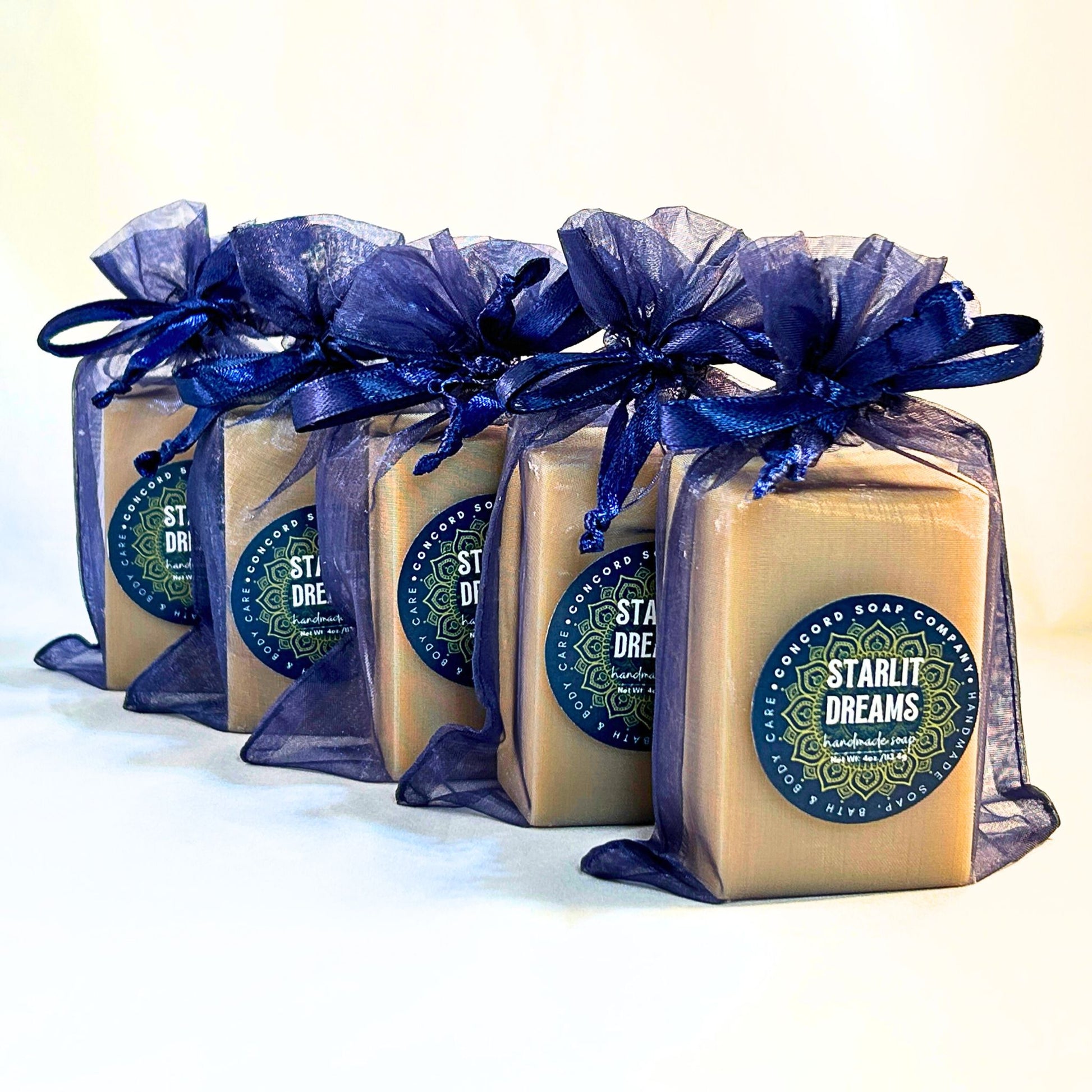 Five Starlit Dreams vegan handmade cold process soap bars in navy organza bags, displayed diagonally with Concord Soap Company product labels.