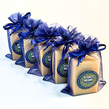 Row of Starlit Dreams handmade cold process soap bars wrapped in navy organza bags on a white background.