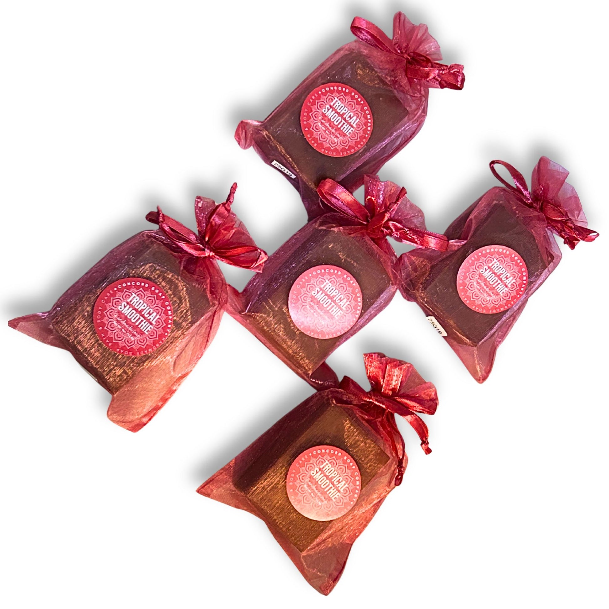 Five Tropical Smoothie soap bars fanned out for an overhead product shot, each in a bright pink organza bag with label. 