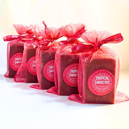 Five Tropical Smoothie handmade soap bars in bright pink organza gift bags with round Concord Soap Company labels, lined in a row. 