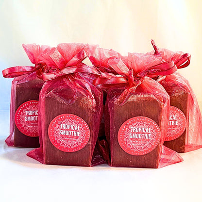 Front-facing group of five Tropical Smoothie handmade soaps in bright pink organza bags, labels visible against a light background. 