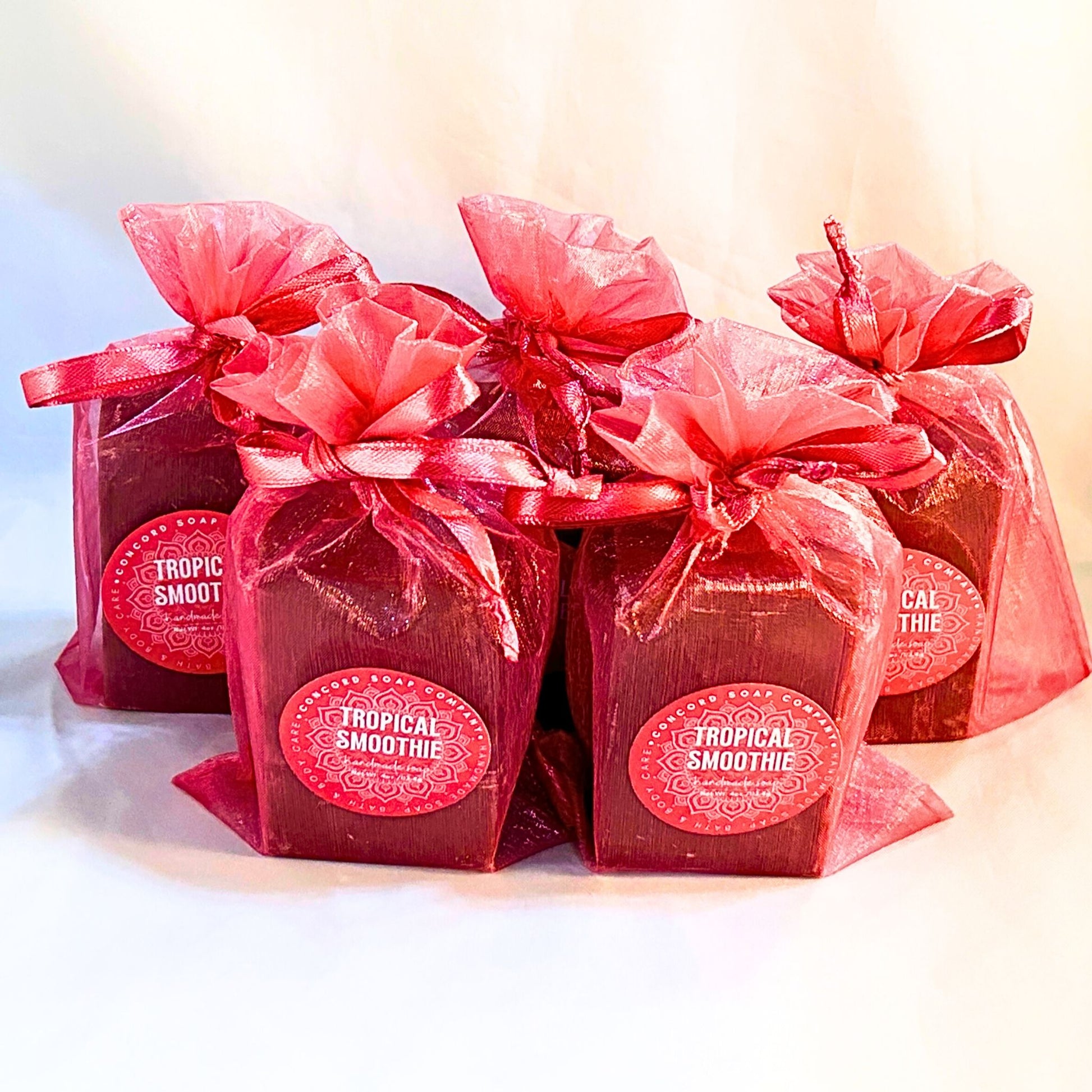 Cluster of five Tropical Smoothie handmade soaps grouped closely in bright pink organza bags. 
