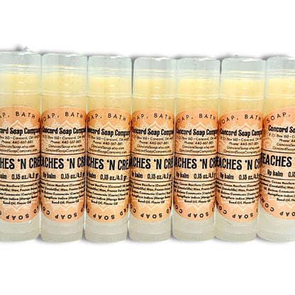 A line of Handmade Peaches & Cream lip balm tubes. Each of these natural lip balms by Concord Soap Company has a peach-colored circle label with product and company details and is shrink wrapped for safety.