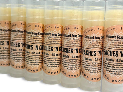 Handmade Peaches & Cream lip balm tubes angled in a slight diagonal line. Each of these natural lip balms by Concord Soap Company has a peach-colored circle label with product and company details and is shrink wrapped for safety.