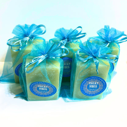 Angled front view of Vacay Vibes natural handmade soap bars, aqua organza bags tied with ribbon, sun and sand scent, vegan soap collection.