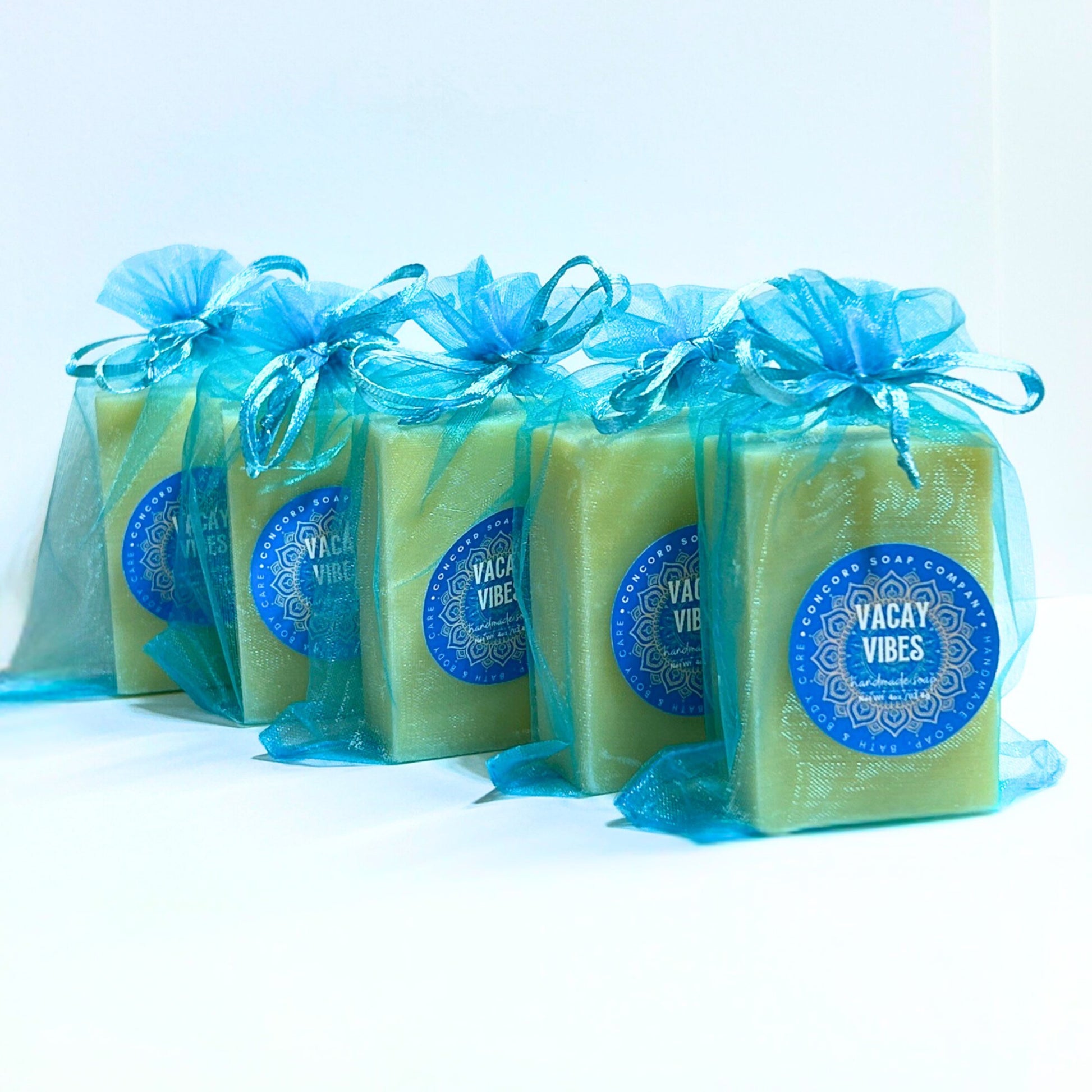 Diagonal row of multiple Vacay Vibes handmade soaps in aqua organza bags, tropical beach-inspired scent with suntan lotion aroma.