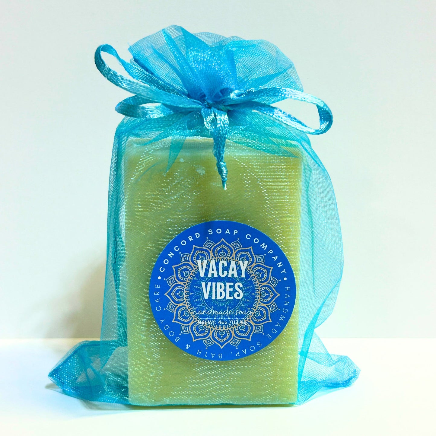 Vacay Vibes handmade soap bar from Concord Soap Company in an aqua organza bag with blue round label, natural vegan cold process soap with beach and suntan lotion scent