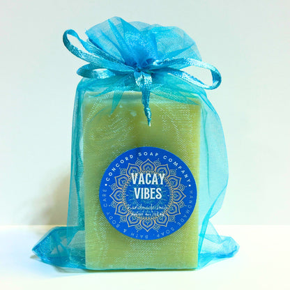 Vacay Vibes handmade soap bar from Concord Soap Company in an aqua organza bag with blue round label, natural vegan cold process soap with beach and suntan lotion scent