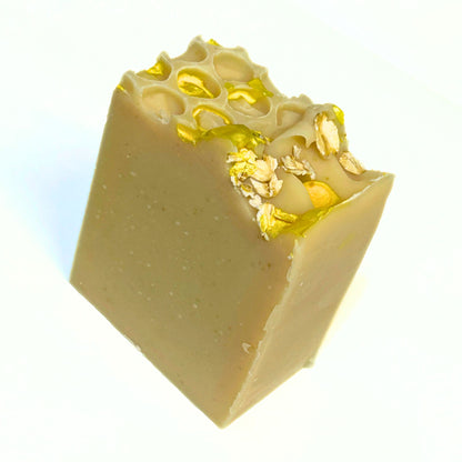 Angled view of the soap showing the honeycomb impression on top with gold mica drizzles and whole oats.