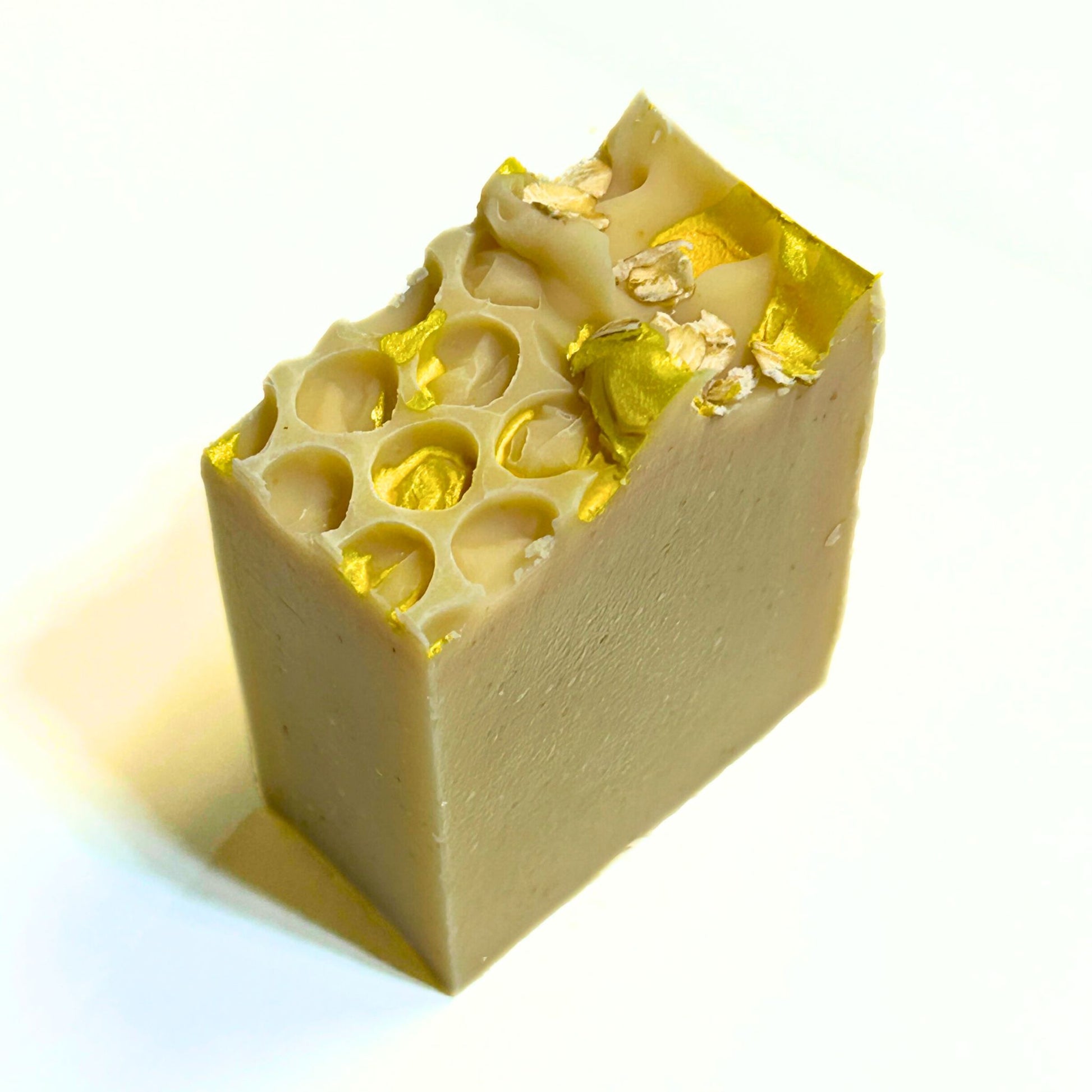 Another angled shot of the soap bar’s honeycomb top decorated with oats and gold mica highlights.