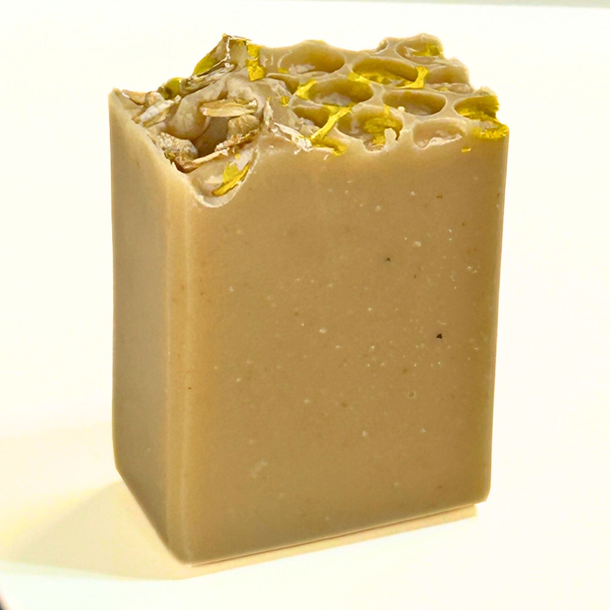 Unpackaged, single Oat, Goat & Honey soap bar standing upright, featuring the honeycomb-style top with oats and gold mica.