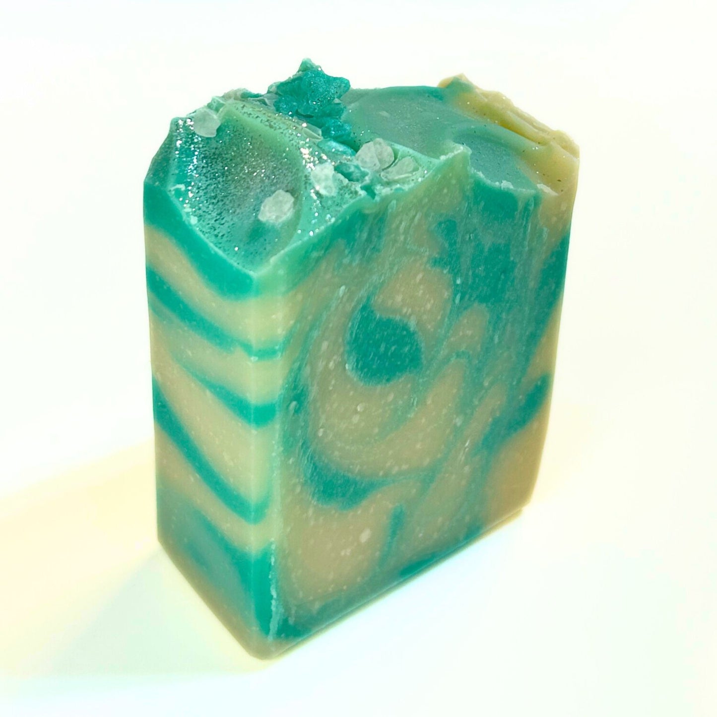 Unwrapped Comfort & Joy soap bar standing upright, showing teal and cream layered swirls.