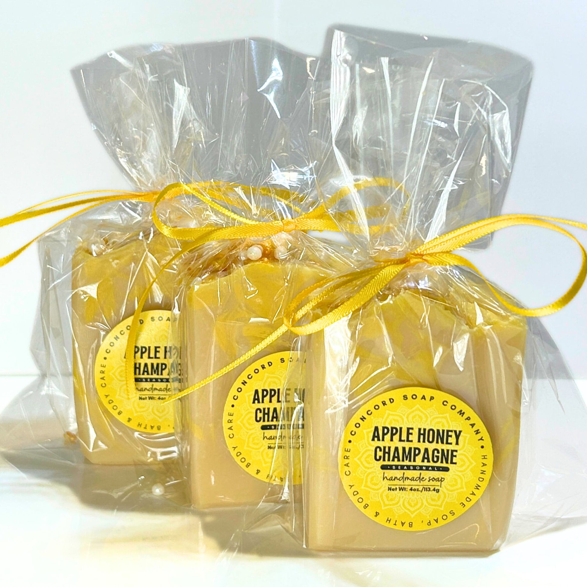 Three Apple Honey Champagne soap bars wrapped in clear cello bags with yellow ribbons.