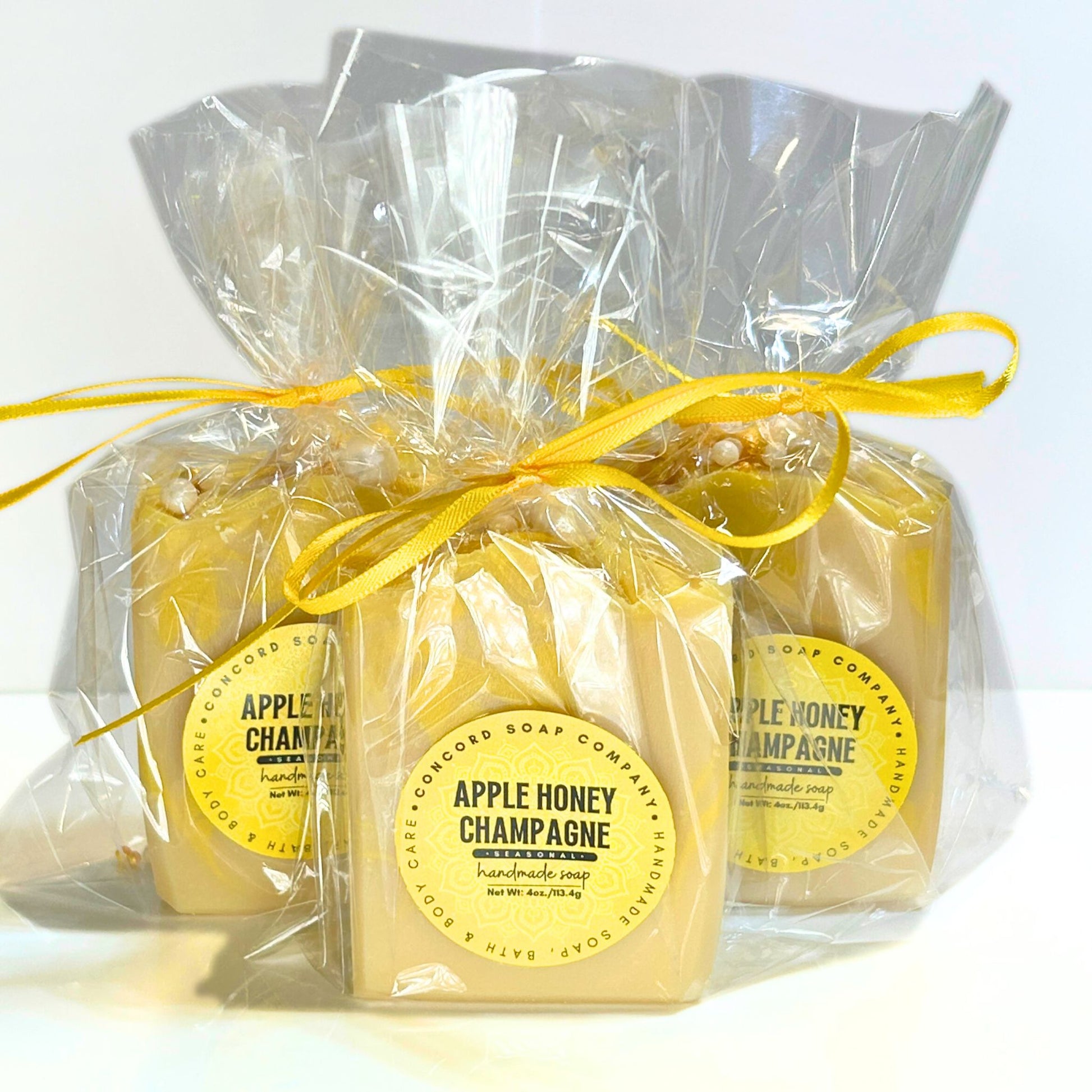 Front view of Apple Honey Champagne soaps in clear gift bags tied with yellow bows.