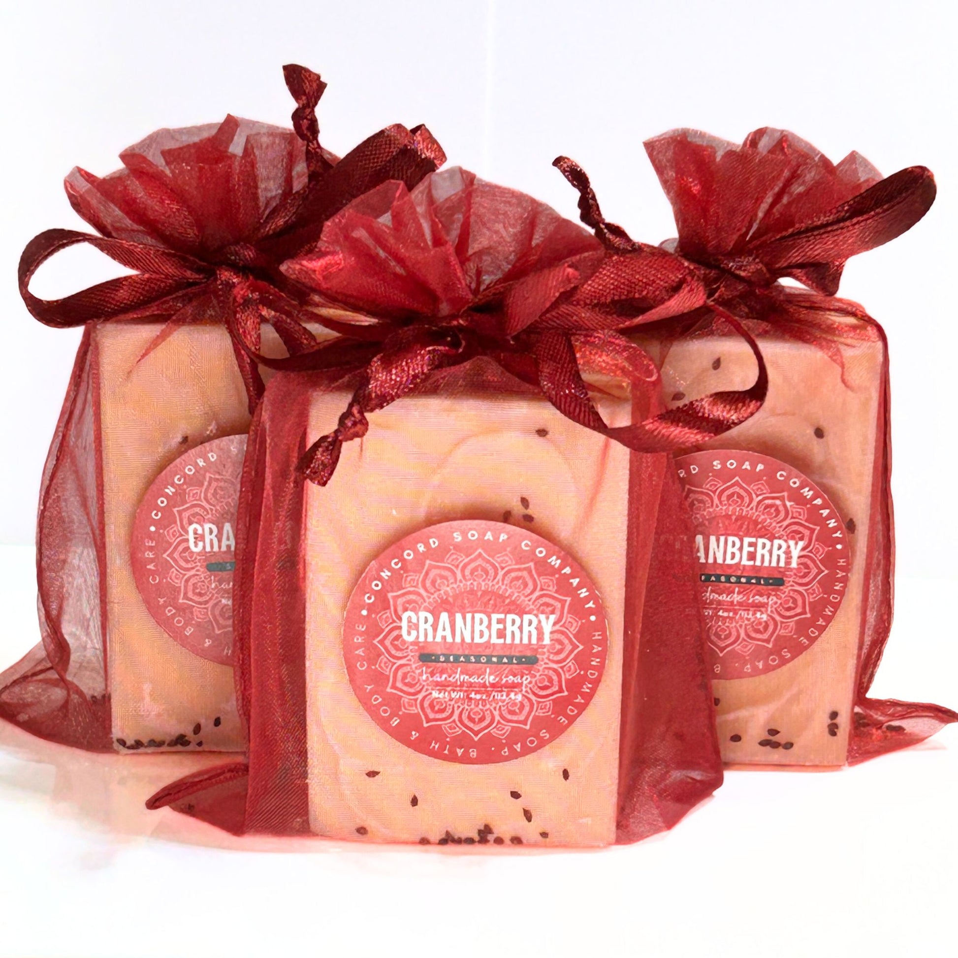 Angled group view of three Cranberry soaps in burgundy organza bags.