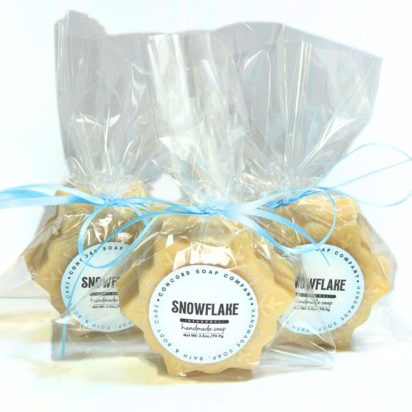 Three individually wrapped Snowflake soap bars in clear cellophane with blue ribbons and round Snowflake labels.