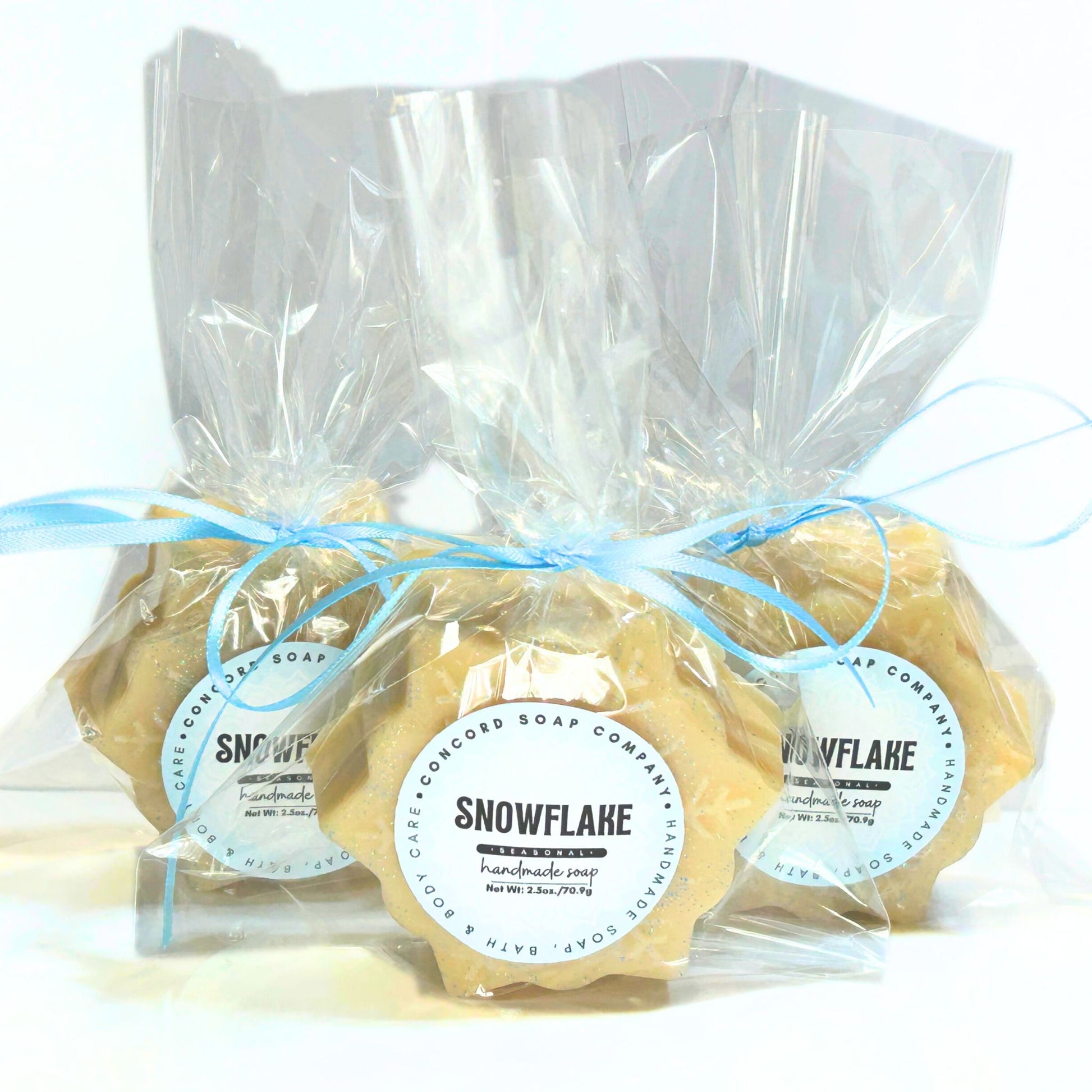 Three individually wrapped Snowflake soap bars in clear cellophane with blue ribbons and round Snowflake labels.