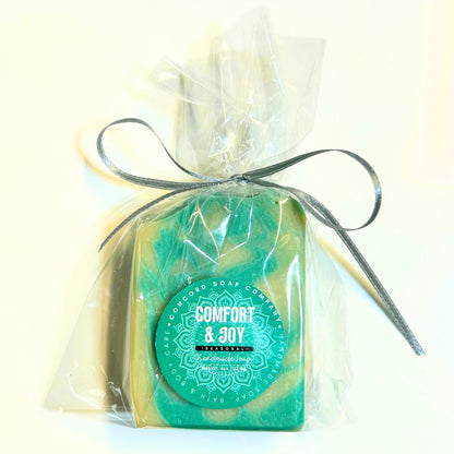 Flay lay view of a single wrapped Comfort & Joy soap bar tied with a silver ribbon against a light background.