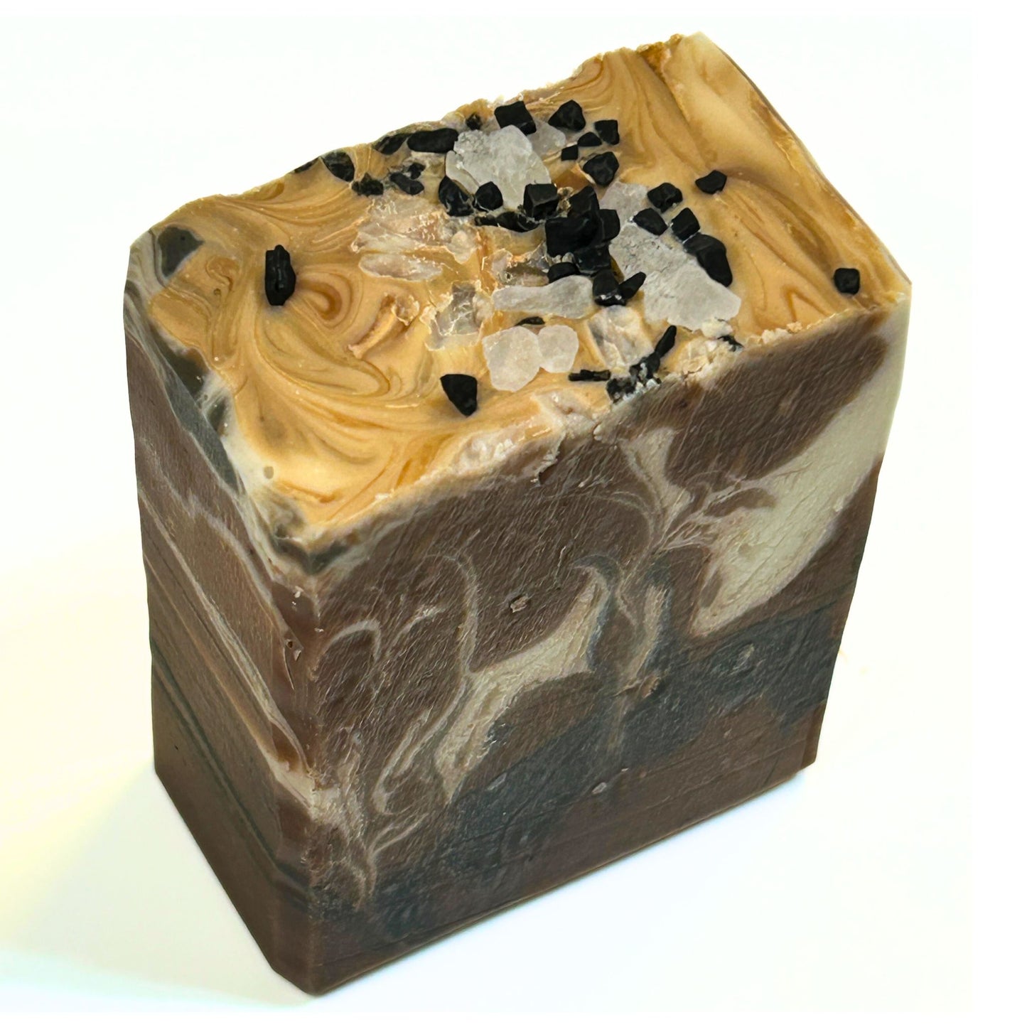 Angled view of the soap bar showing the tan and brown swirl pattern with black and white salt crystals sprinkled on top.