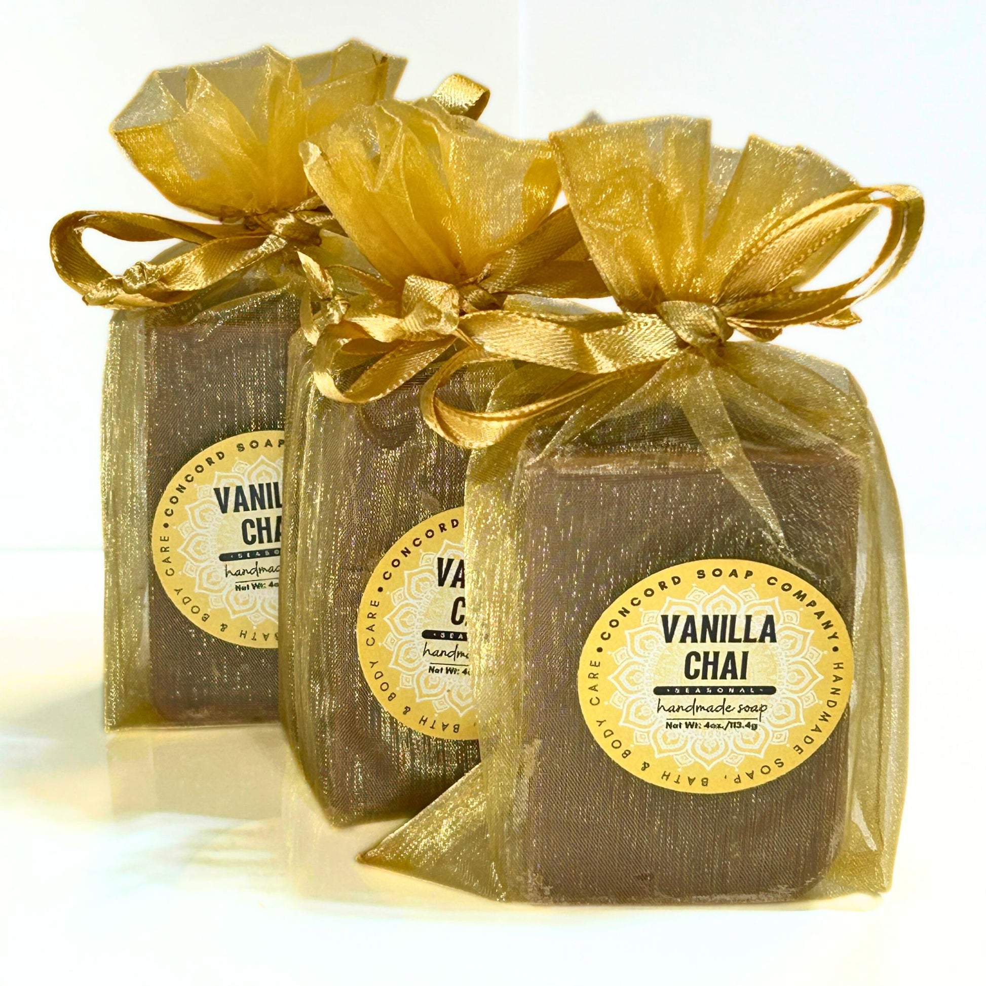 View of three Vanilla Chai soap bars in gold organza bags arranged in a diagonal line.