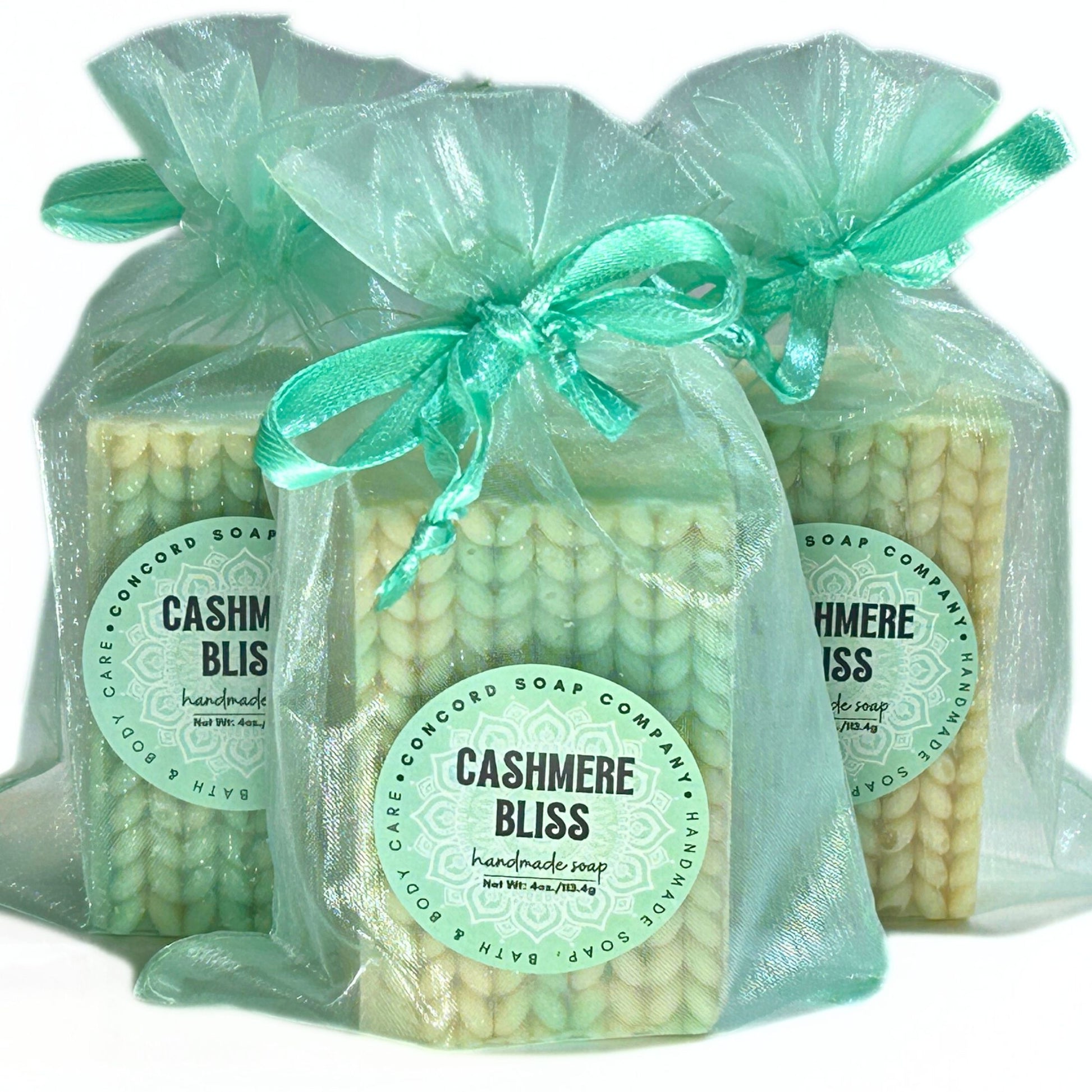 Three Cashmere Bliss soap bars wrapped in light aqua organza bags with matching ribbons.