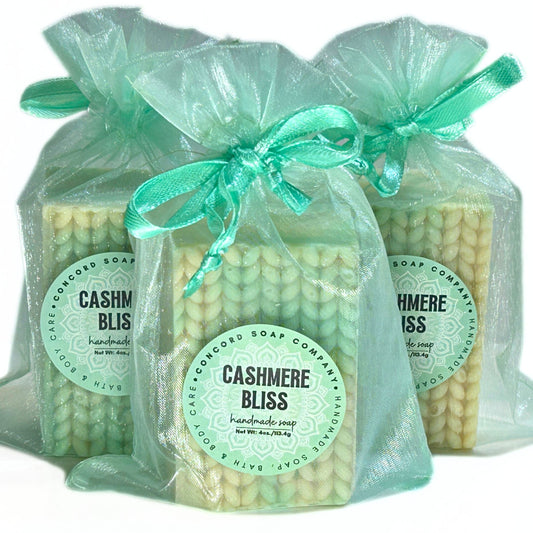 Three Cashmere Bliss soap bars wrapped in light aqua organza bags with matching ribbons.