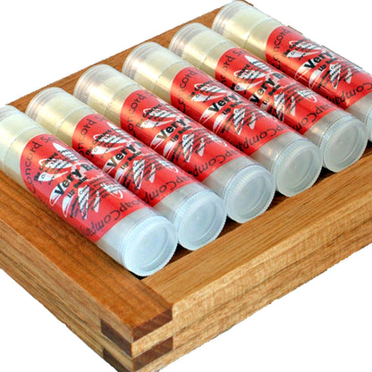 Handmade Very Berry Sparkle lip balm tubes with red labels arranged together on a wood dish, photographed on a clean white background.
